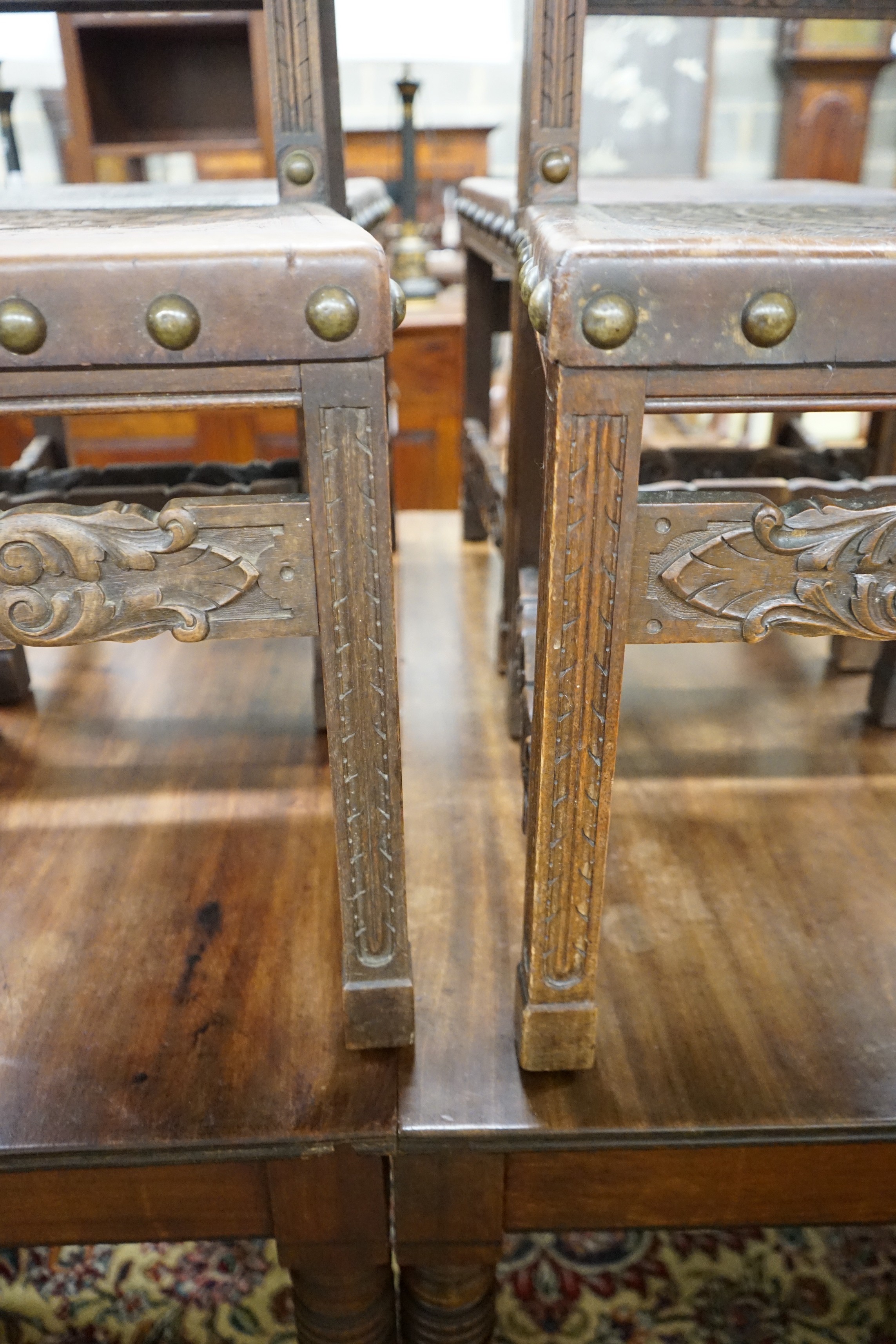A set of six 18th century style brass studded carved oak and embossed leather dining chairs